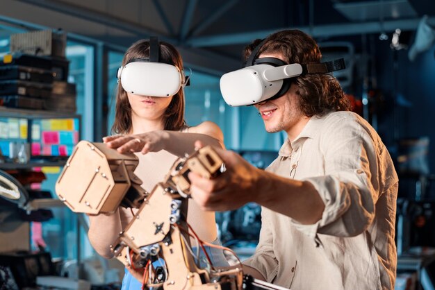 Hombre y mujer jóvenes con gafas protectoras haciendo experimentos en robótica en un robot de laboratorio