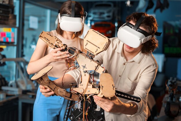 Hombre y mujer jóvenes con gafas protectoras haciendo experimentos en robótica en un robot de laboratorio