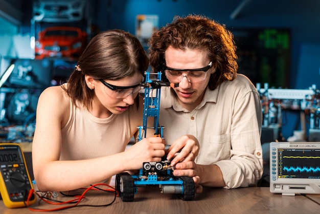 Hombre y mujer jóvenes con gafas protectoras haciendo experimentos en robótica en un robot de laboratorio