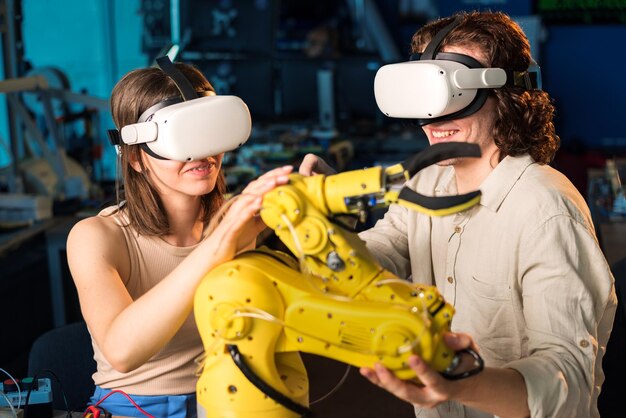 Hombre y mujer jóvenes con gafas VR haciendo experimentos en robótica en un laboratorio Robot y herramientas