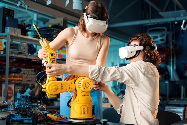 Hombre y mujer jóvenes con gafas VR haciendo experimentos en robótica en un laboratorio Robot y herramientas