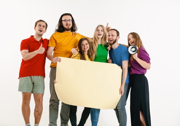 El hombre y la mujer jóvenes vestían los colores de la bandera LGBT en la pared blanca. modelos con camisas brillantes