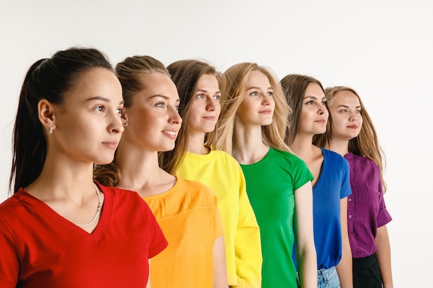 El hombre y la mujer jóvenes vestían los colores de la bandera LGBT en la pared blanca. modelos con camisas brillantes