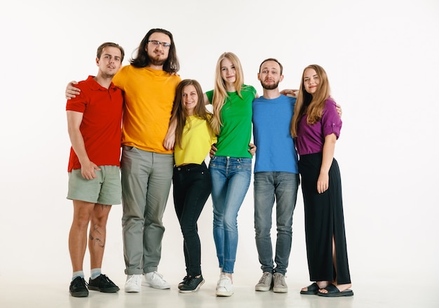 El hombre y la mujer jóvenes vestían los colores de la bandera LGBT sobre fondo blanco. Modelos caucásicos con camisas brillantes.