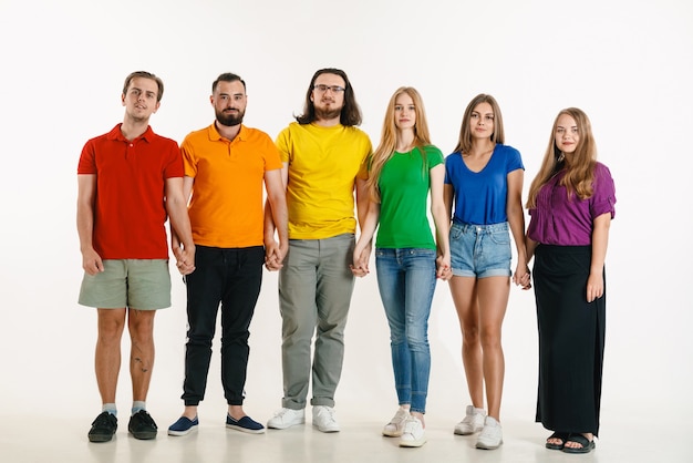 El hombre y la mujer jóvenes vestían los colores de la bandera LGBT sobre fondo blanco. Modelos caucásicos con camisas brillantes.