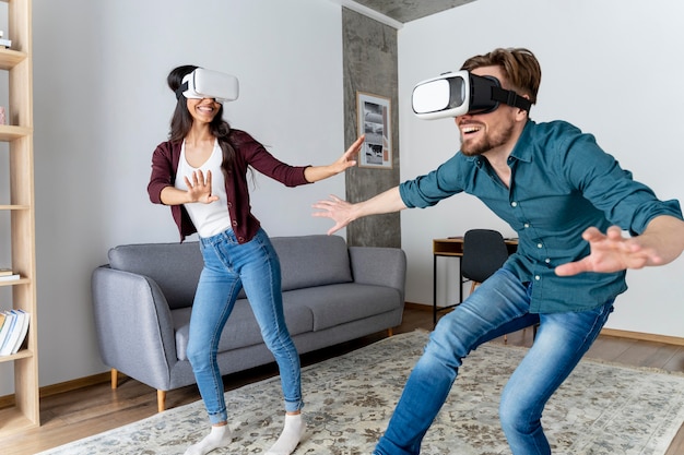 Hombre y mujer juegan juntos con casco de realidad virtual en casa