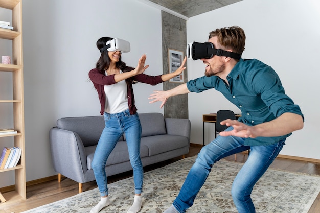 Hombre y mujer juegan juntos con casco de realidad virtual en casa