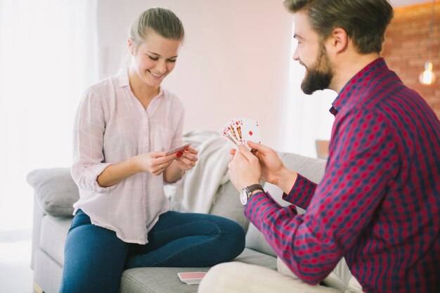 Hombre y mujer jugando a las cartas en el sofá