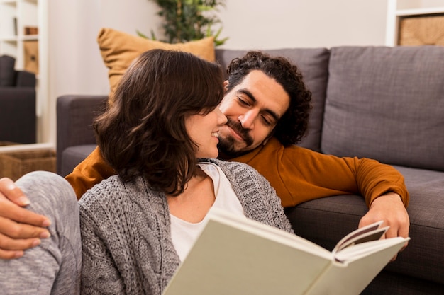 Hombre y mujer leyendo juntos en la sala de estar