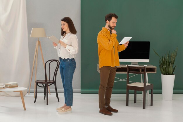 Hombre y mujer leyendo libros y usando tableta