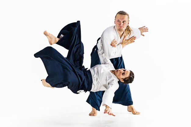 Hombre y mujer luchando y entrenando aikido en la pared blanca del estudio