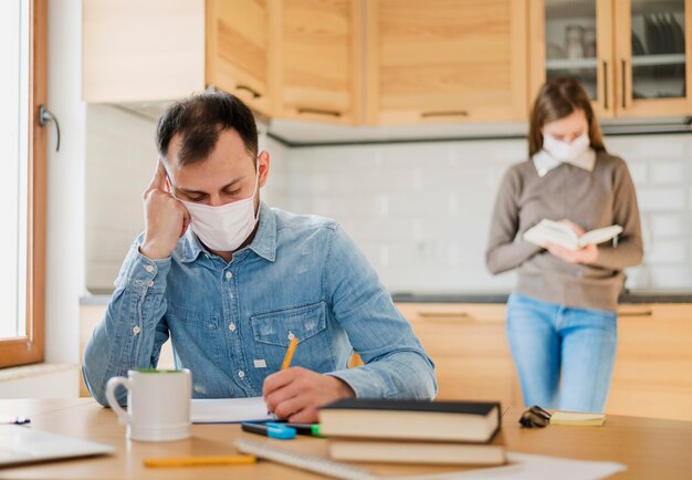 Hombre y mujer con máscaras médicas aprendiendo desde casa