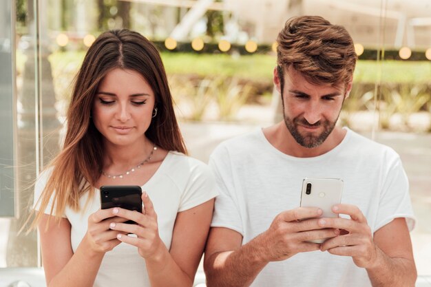 Hombre y mujer con mensajes de texto de teléfonos inteligentes