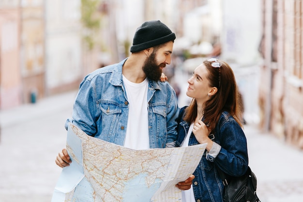 El hombre y la mujer miran el mapa de pie en algún lugar de una ciudad vieja