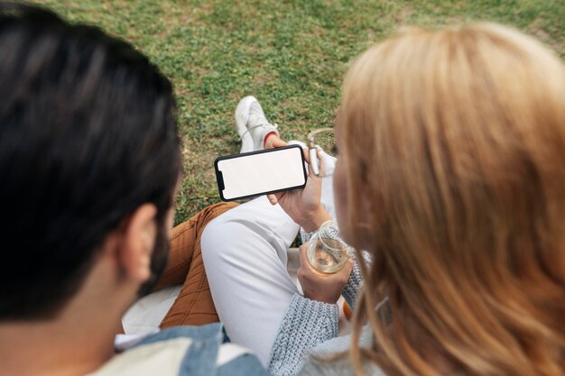 Hombre y mujer mirando un teléfono mientras hace un picnic