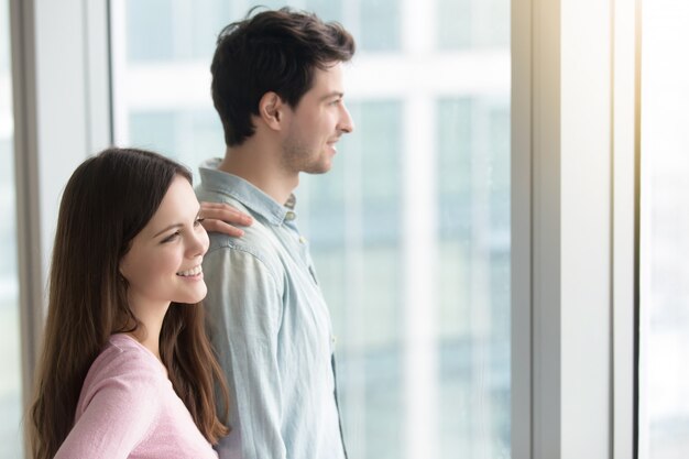 Hombre y mujer mirando por la ventana al paisaje de la ciudad