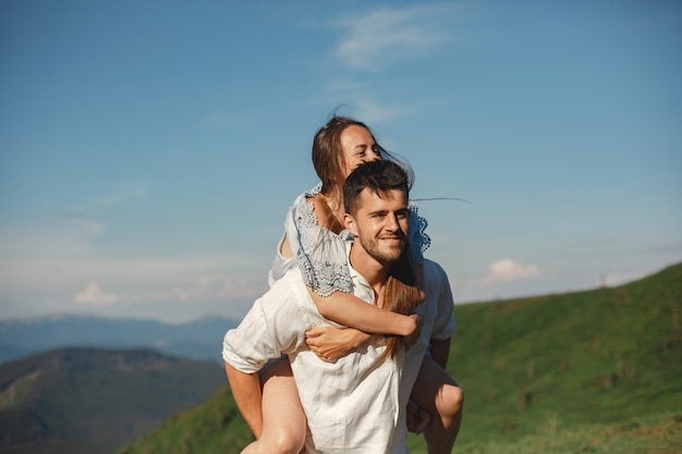 Hombre y mujer en las montañas. Joven pareja de enamorados al atardecer. Mujer con un vestido azul.