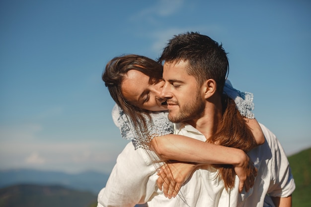 Hombre y mujer en las montañas. Joven pareja de enamorados al atardecer. Mujer con un vestido azul.