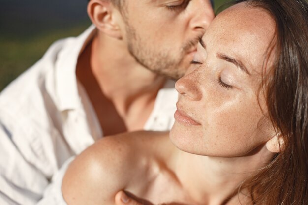 Hombre y mujer en las montañas. Joven pareja de enamorados al atardecer. Mujer con un vestido azul.