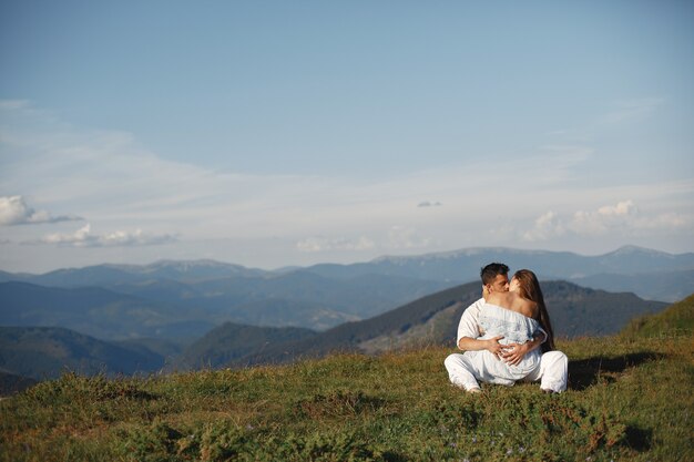 Hombre y mujer en las montañas. Joven pareja de enamorados al atardecer. Mujer con un vestido azul.