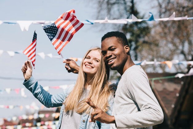 Hombre y mujer multiétnica con banderas americanas