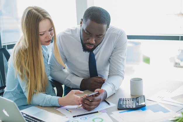 Hombre y mujer de negocios inclinandose sobre escritorio