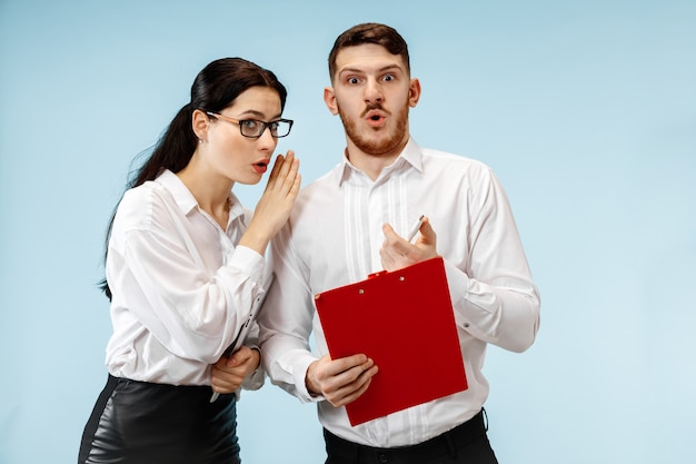 El hombre y la mujer de negocios sorprendidos sonriendo sobre un fondo azul de estudio