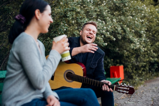 Hombre y mujer pasar tiempo junto con la guitarra al aire libre