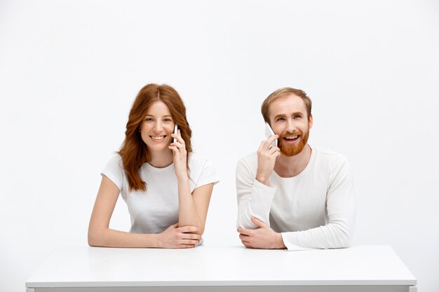 Hombre y mujer pelirroja feliz hablan teléfono móvil