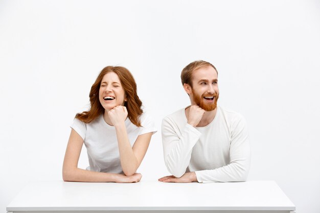 Hombre y mujer pelirroja feliz riéndose de la mesa