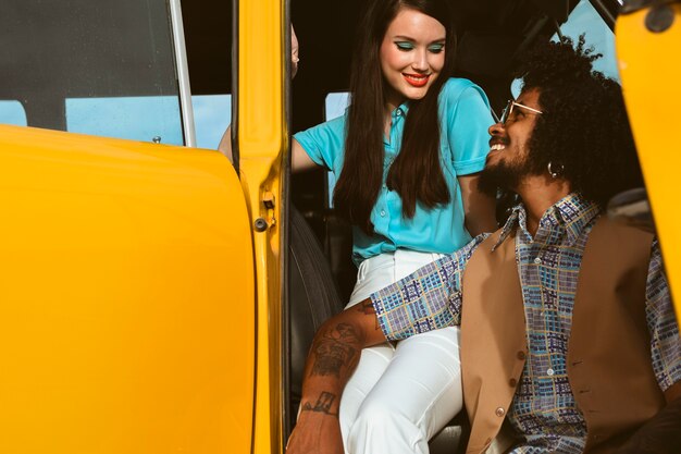 Hombre y mujer posando en estilo retro con coche.