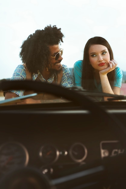 Hombre y mujer posando en estilo retro con coche.