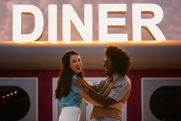 Hombre y mujer posando en estilo retro fuera del restaurante