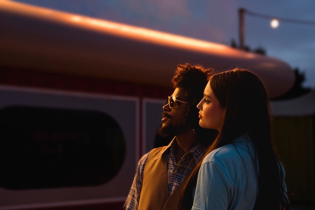 Hombre y mujer posando juntos en estilo retro por la noche con luces