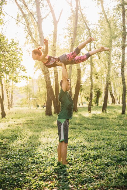 Hombre y mujer practicando acroyoga en jardín