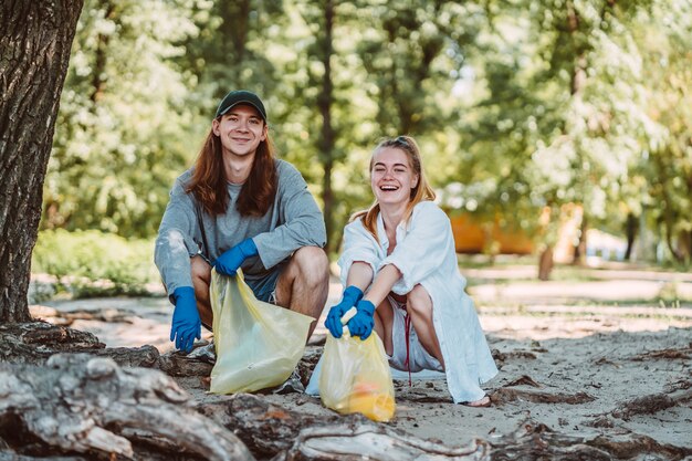 Hombre y mujer recogiendo basura del parque. Recogen la basura en la bolsa de basura