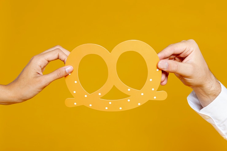 Foto gratuito hombre y mujer con réplica de pretzel
