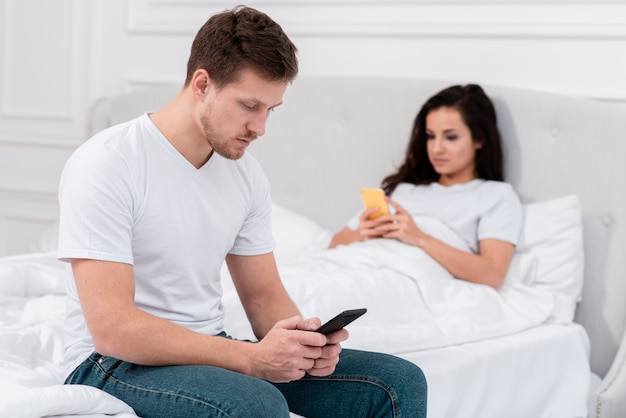 Hombre y mujer revisando su teléfono después de despertarse