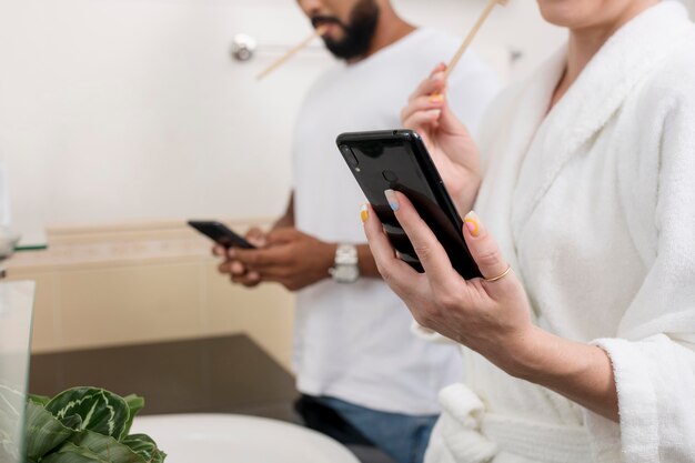 Hombre y mujer revisando sus teléfonos incluso en su baño