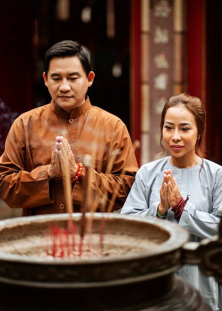 Hombre y mujer rezando en el templo con incienso