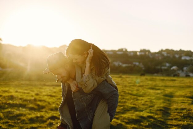 Hombre y mujer en ropa de moda descansando sobre una naturaleza juntos al atardecer