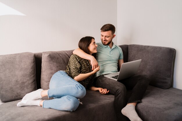 Hombre y mujer sentada en el sofá con una computadora portátil