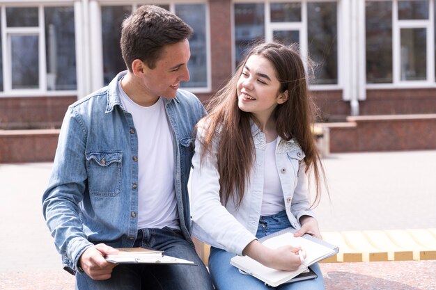 Hombre y mujer sentados juntos con libros abiertos