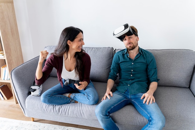 Hombre y mujer sentados en el sofá en casa con casco de realidad virtual