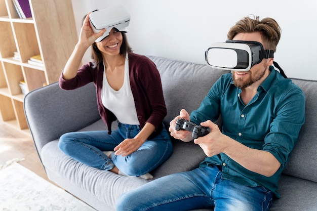 Hombre y mujer sentados en el sofá en casa y con casco de realidad virtual