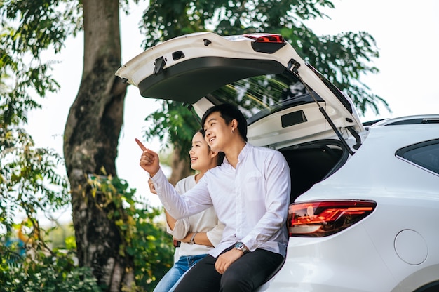 El hombre y la mujer se sentaron felices en el maletero del coche.