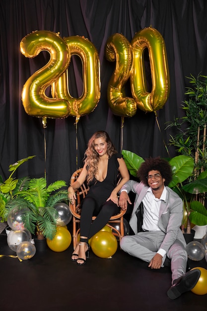 Hombre y mujer sonriendo y globos de año nuevo 2020