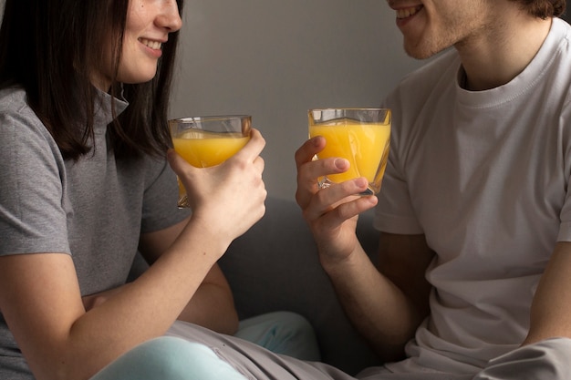 Hombre y mujer sonriendo y sosteniendo jugo de naranja