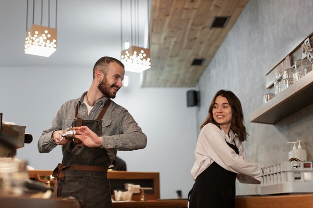 Hombre y mujer sonriendo y trabajando en la cafetería.