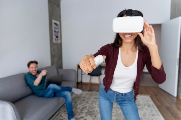 Hombre y mujer sonriente divirtiéndose en casa con casco de realidad virtual